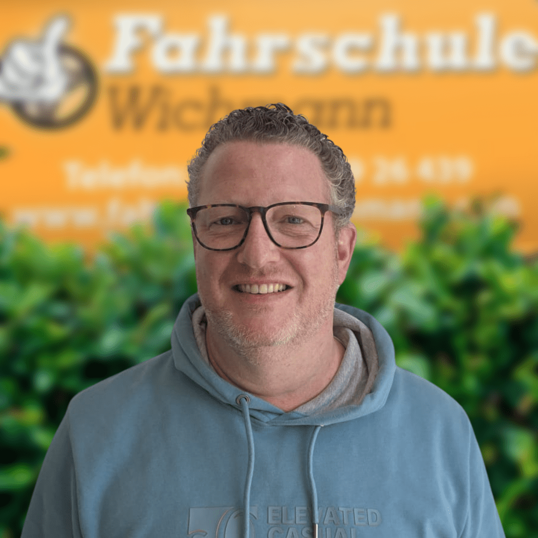 Oli-Fahrlehrer-Fahrschule-Wichmann- - Fahrschule Wichmann Lemwerder - Autoführerschein LKW Führerschein Motorradführerschein Fahrlehrer Torben von der Fahrschule Wichmann in Delmenhorst vor dem gelben Firmenschild.